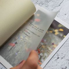 a person is holding an open book with flowers on it and the pages are white