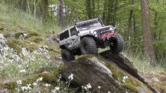 a jeep driving over a rock in the woods