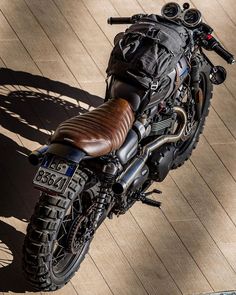 a black motorcycle parked on top of a wooden floor next to a bag filled with luggage