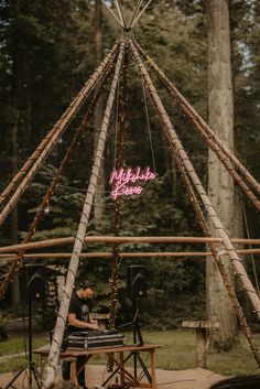 a man sitting at a table in front of a teepee with lights on it