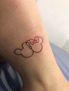 a small tattoo on the leg of a person with a red bow in her hair