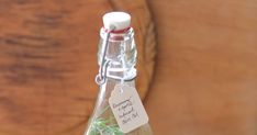 a glass bottle filled with liquid sitting on top of a wooden table next to a plant