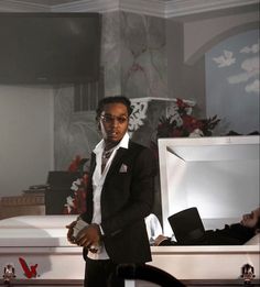 a man in a suit and tie standing next to a white box with flowers on it