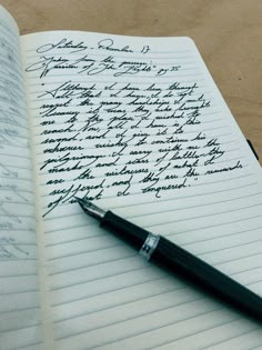 an open notebook with writing on it and a fountain pen resting on the page next to it