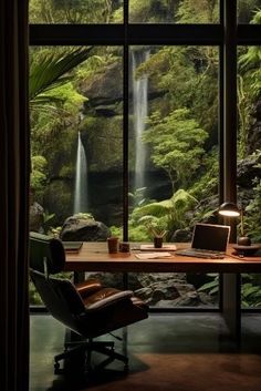 a desk with a laptop on it in front of a window that has a view of a waterfall