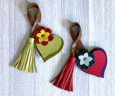 two paper hearts with tassels and flowers on them