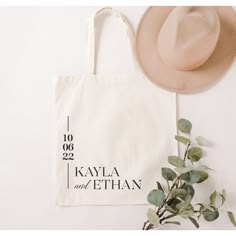 a tote bag with the date printed on it next to a hat and eucalyptus