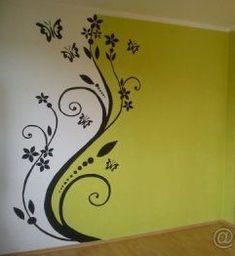 an empty room with yellow walls and black flowers painted on the wall, along with a wooden floor