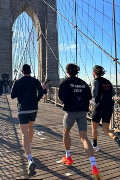 three people running across the brooklyn bridge