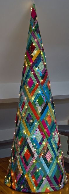 a multicolored christmas tree with lights on it's sides and the top is made out of strips of fabric