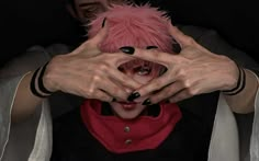 a person with pink hair holding their hands up to their face while wearing black and white makeup