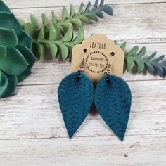 the leather earrings are blue and have two leaves on them, one is shaped like a leaf