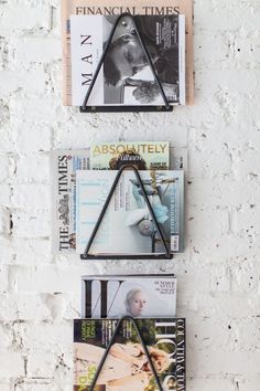 three books are stacked on top of each other in front of a white brick wall