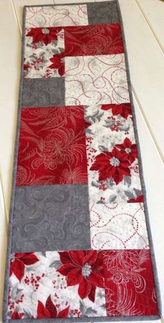 a red and white quilted table runner with poinsettis on the side