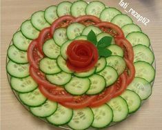 a plate with cucumbers and tomatoes arranged in the shape of a spiral on top of each other