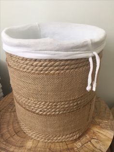 a large round basket on top of a tree stump with rope around the bottom and sides