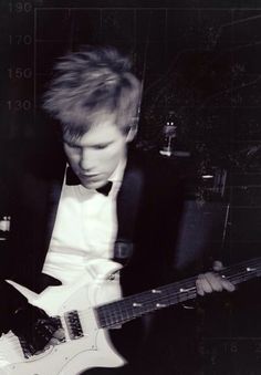 a young man in a tuxedo plays an electric guitar while wearing a bow tie