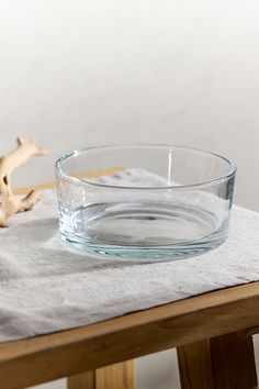 a glass bowl sitting on top of a table next to a piece of driftwood