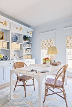 a dining room table with two chairs and a lamp on top of it in front of a bookshelf