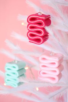 three felt ornaments hanging from a white christmas tree with pink and blue decorations on it