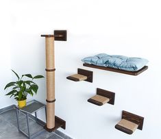 a cat scratching station with three shelves and a bed on the wall next to it