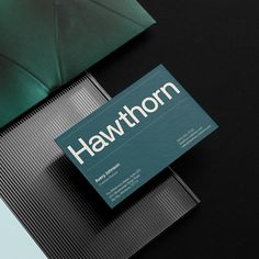 a business card sitting on top of a black table next to an open green umbrella