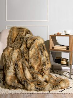 a fur blanket sitting on top of a wooden floor next to a chair and table