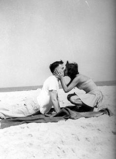 an old photo of two people kissing on the beach