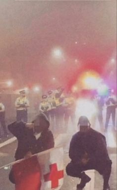 a group of people standing on the side of a road with police in the background