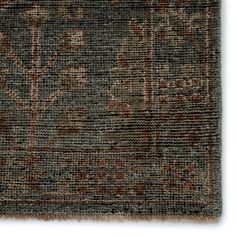 a rug with an intricate design on the front and side, in dark grey tones