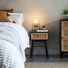 a bedroom with two nightstands and a bed next to each other in front of a gray wall