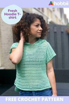 a woman with curly hair wearing a green crochet top and holding her hand to her ear