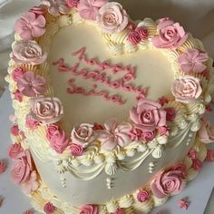 a heart shaped birthday cake with pink roses on it's edges and the words happy birthday written in frosting