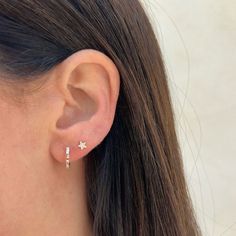 a close up of a person's ear wearing a pair of earrings with stars on them