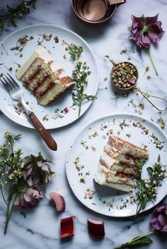 two slices of cake sitting on top of white plates next to flowers and silverware