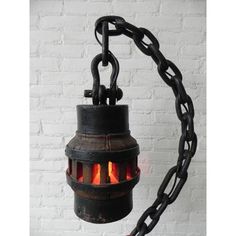 a chain hanging from the side of a white brick wall with a light in it