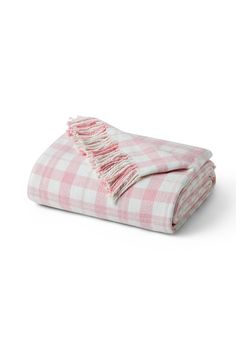 the pink and white checkered blanket is folded on top of each other with fringes