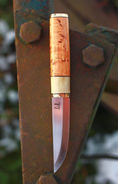 a knife stuck in the side of a rusted metal object with a wooden handle