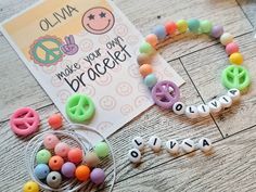 some beads are laying on the floor next to a sign and scissors with letters that spell out names