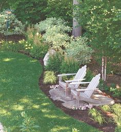 two white lawn chairs sitting on top of a lush green field next to a tree