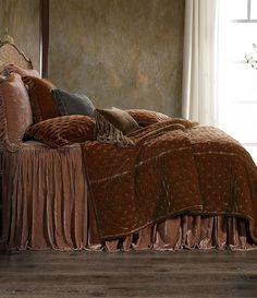 a bed with a brown bedspread and pillows on top of it next to a window