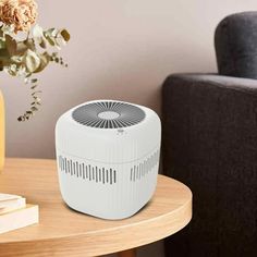 an air conditioner sitting on top of a table next to a vase with flowers