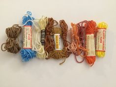 several skeins of yarn are laid out on a white surface, one is orange and the other is blue