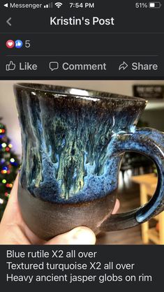 a hand holding a coffee cup with blue and green designs on it, in front of a christmas tree