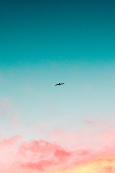 an airplane is flying in the sky at sunset or dawn with pink and blue clouds