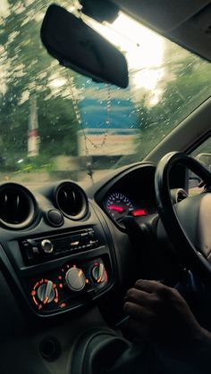 a man driving a car down a street next to trees