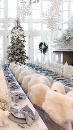 a dining room table set for christmas with snowflakes hanging from the ceiling and decorations