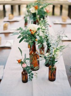 the table is set with vases and flowers