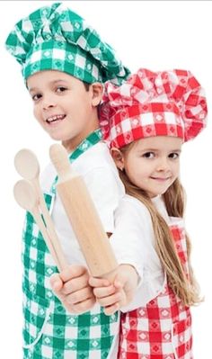 two children in aprons holding wooden utensils