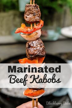 a hand holding a skewer with meat and vegetables on it that says marinated beef kabobs